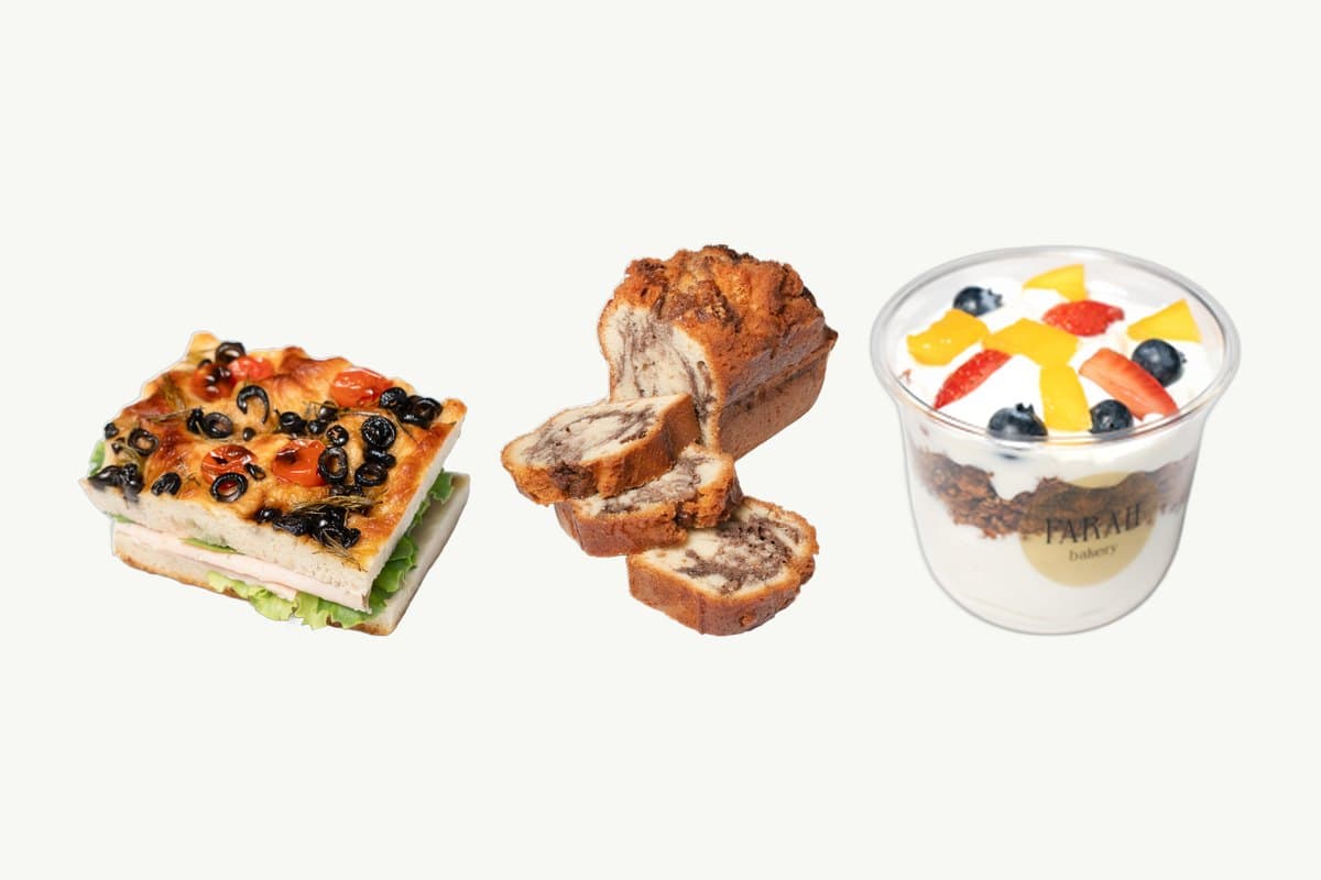 A focaccia smoked turkey sandwich, a sliced marble cake loaf and a granola parfait cup side by side on a plain cream background
