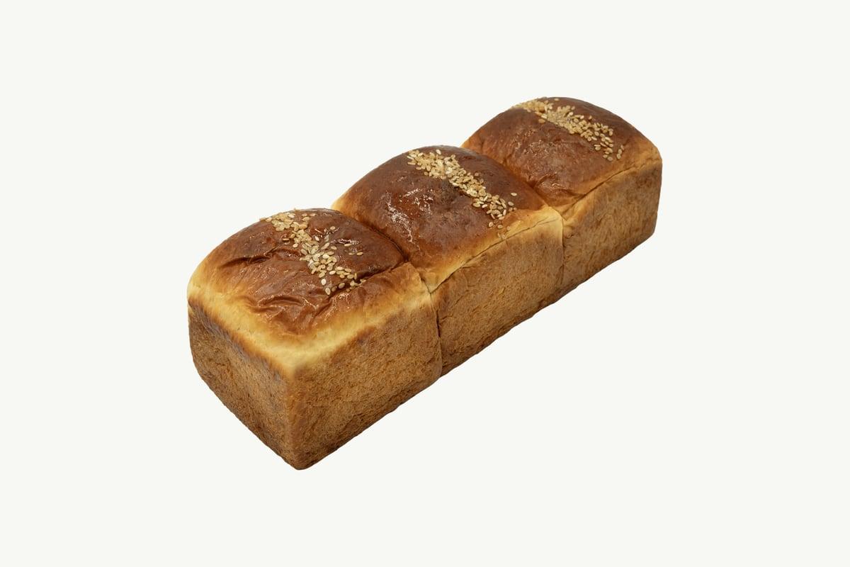 Golden brioche loaf with a rich, tight crumb on plain cream
