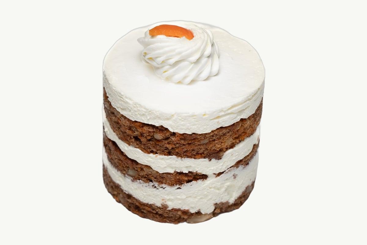 A slice of carrot cake with cream cheese frosting on a plain cream plate
