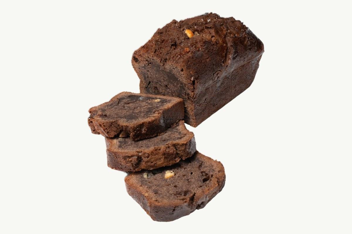 Double chocolate and coconut cake loaf sliced on a plain cream background