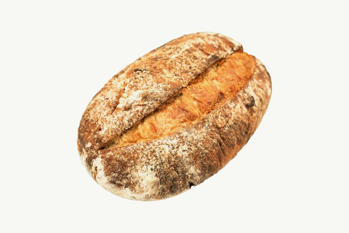 Round sourdough loaf with a scored, deeply browned crust on cream background