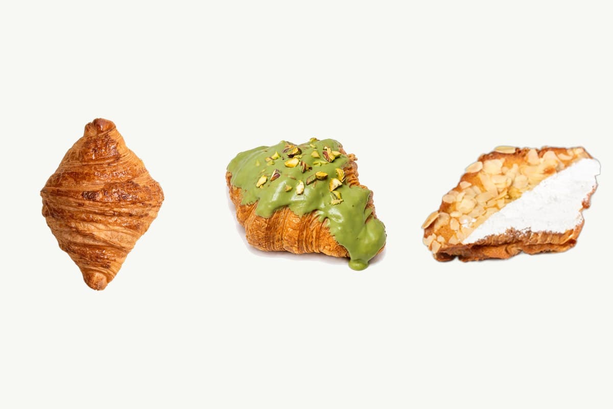 A plain butter croissant, a pistachio croissant and an almond cream croissant on a plain cream background