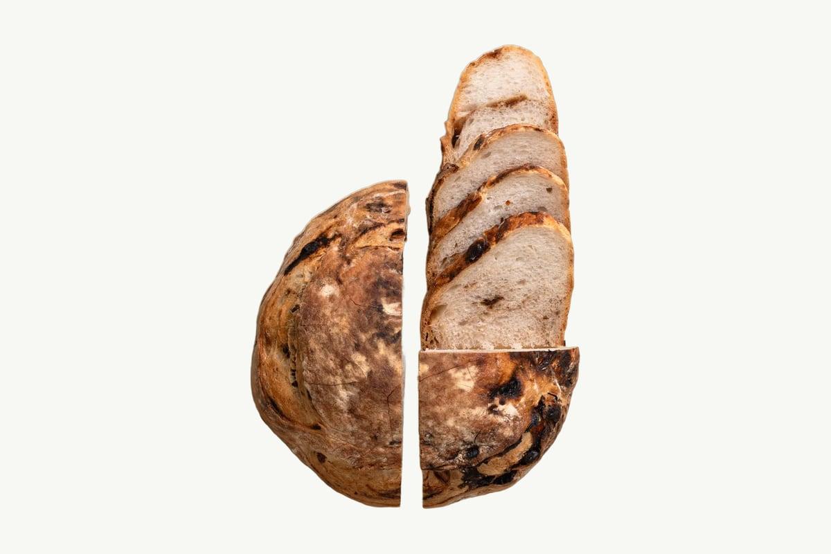 Dark date and walnut sourdough loaf resting on a plain cream background