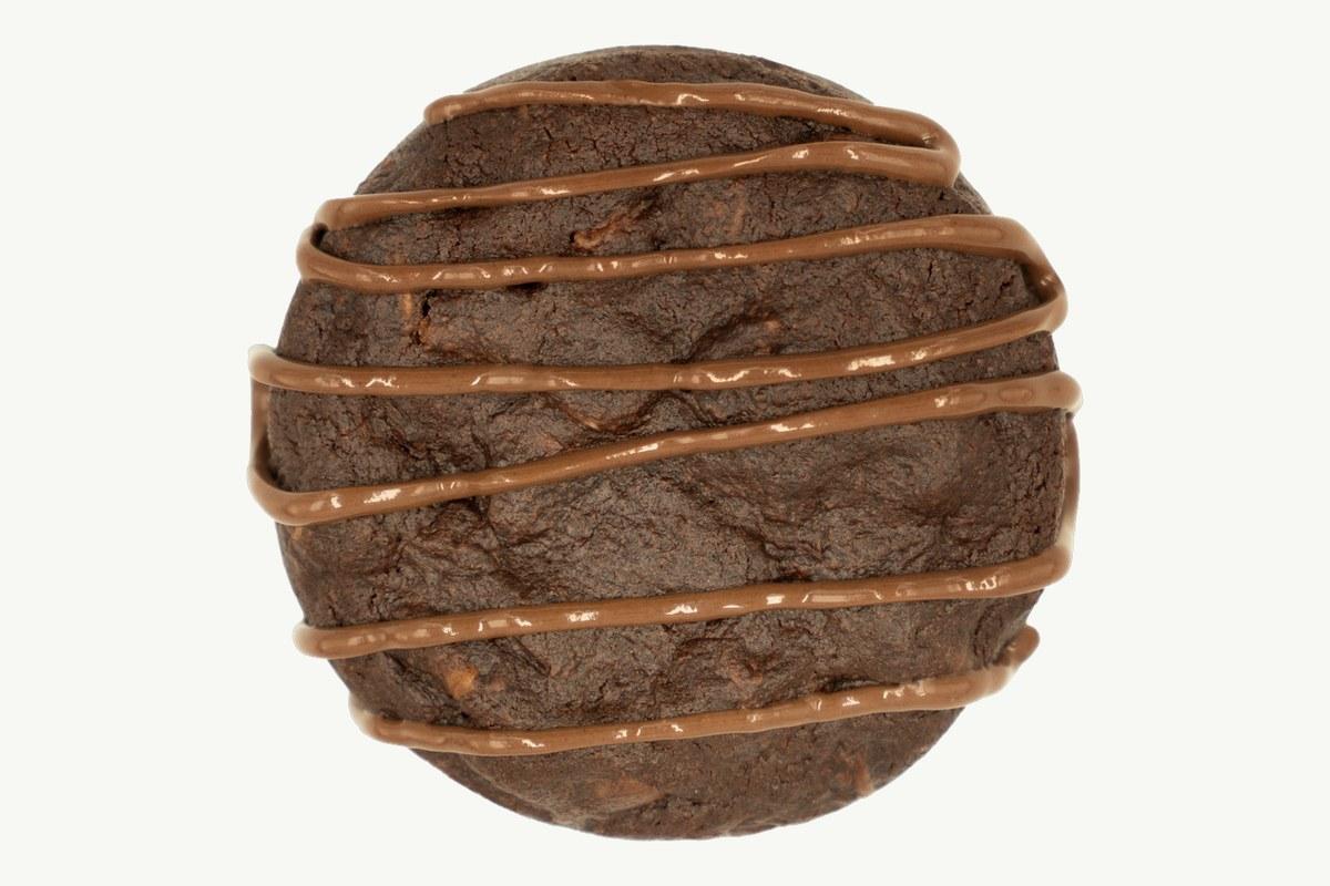Double chocolate chip cookie broken open on a plain cream background