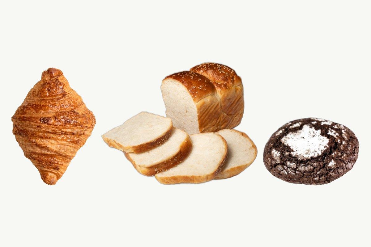 A butter croissant, a sliced Japanese milk bread loaf and a chocolate crinkle cookie on a plain cream background