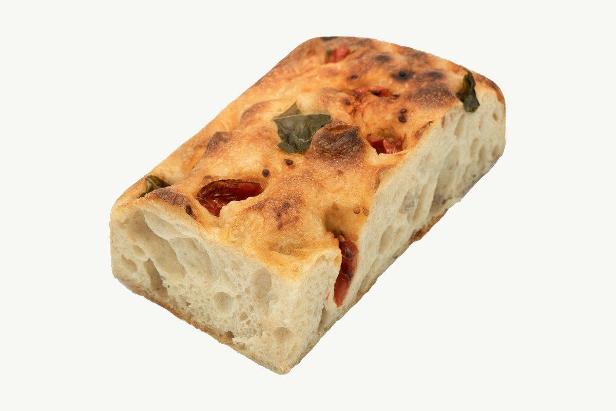 Cherry tomato focaccia slab on a plain cream surface