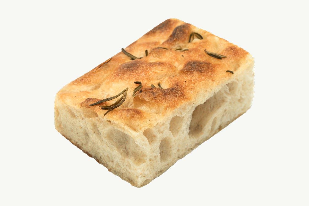 Golden rosemary focaccia slab on a plain cream surface