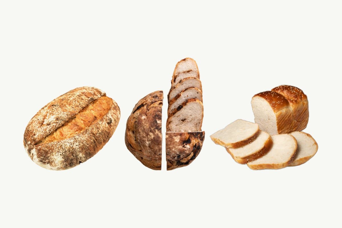 A Country Sourdough Loaf, a Date, Walnut & Honey Sourdough cut in half and sliced, and a sliced Japanese Milk Bread Loaf side by side on a plain cream background