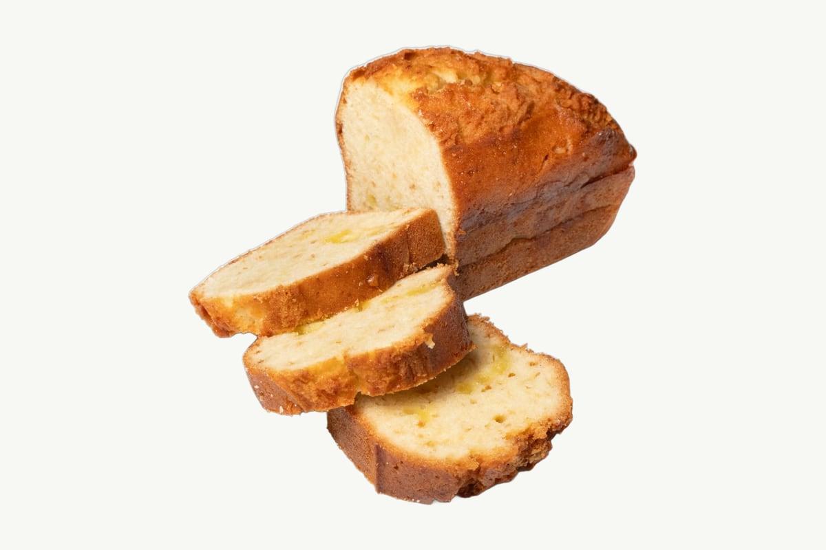Sliced classic lemon butter cake loaf resting on a plain cream background