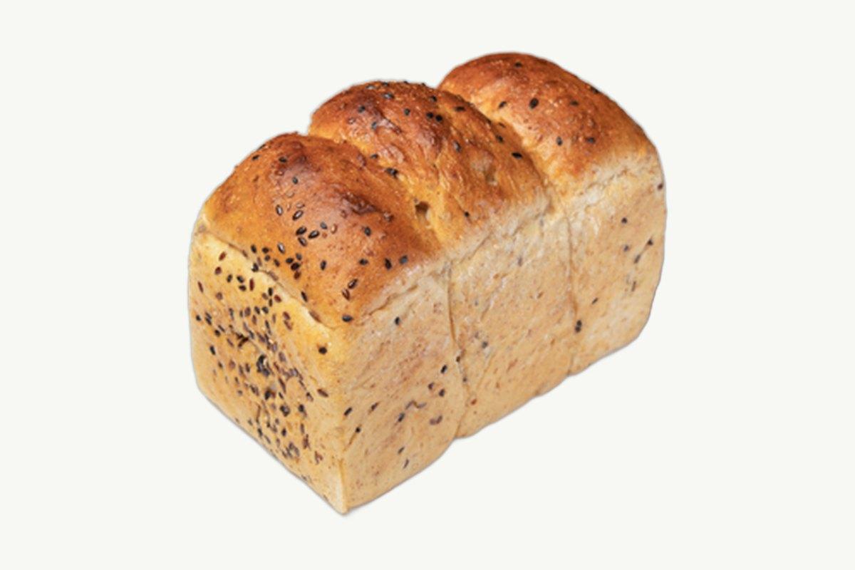 Sliced multi-seed whole wheat toast loaf on a plain cream surface