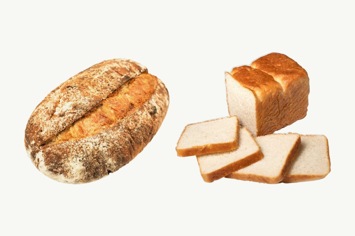A country sourdough loaf beside a sliced white toast loaf on a plain cream background