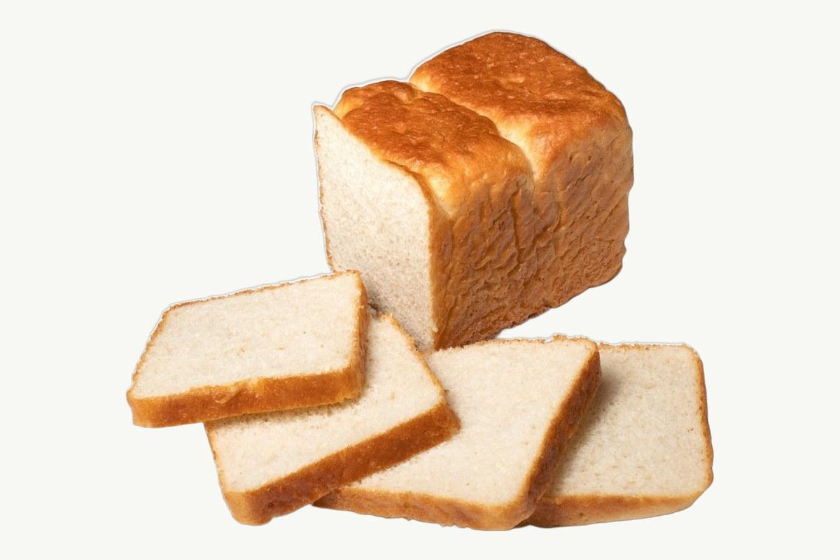 Sliced white toast bread loaf on a plain cream background