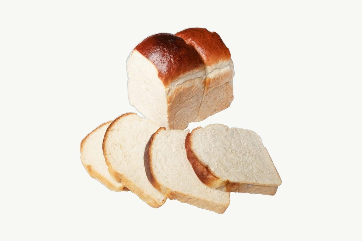 A golden brioche toast loaf standing on a plain cream studio background